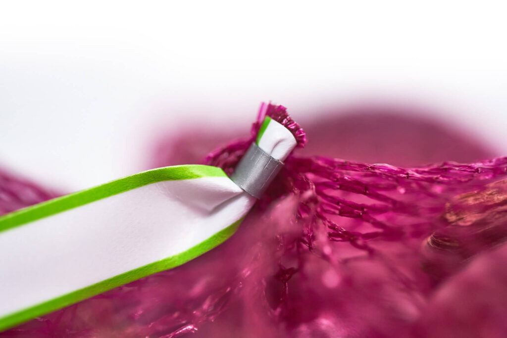 Solipac Clipband in Nahaufnahme – befestigt Stegetikett an Raschelnetz zum sicheren Verschließen von Netzverpackungen.