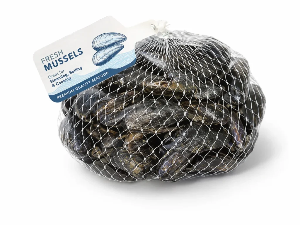 Bag of fresh mussels in a white mesh net with a label reading 'Fresh MUSSELS' and notes 'Great for Steaming, Boiling & Cooking' — premium seafood.